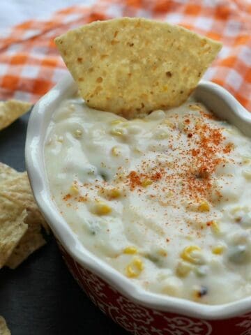 Oval dish with creamy grilled corn and jalapeno queso dip.