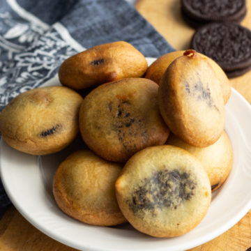 Browned fried Oreo cookies piled on a white plate.