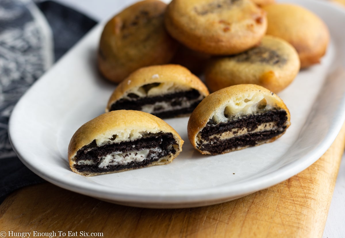 White plate with fried Oreos and three fried Oreos cut in half