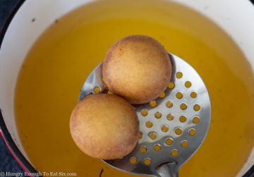 Two fried Oreos on a slotted spoon over a pan of hot oil