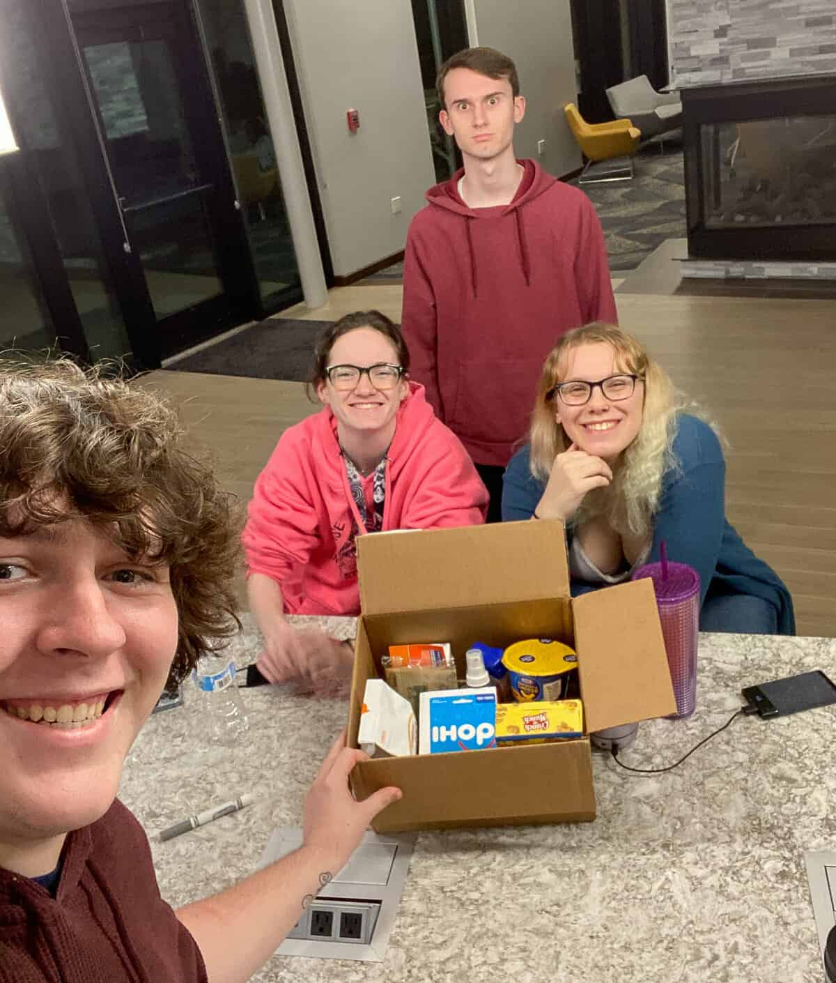 Four fun loving college students with a care package box of treats.