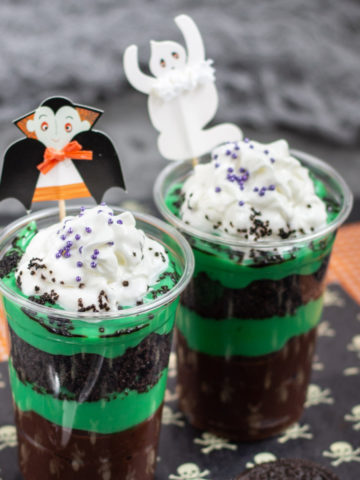 Clear shiny plastic cups with layers of green and brown chocolate pudding