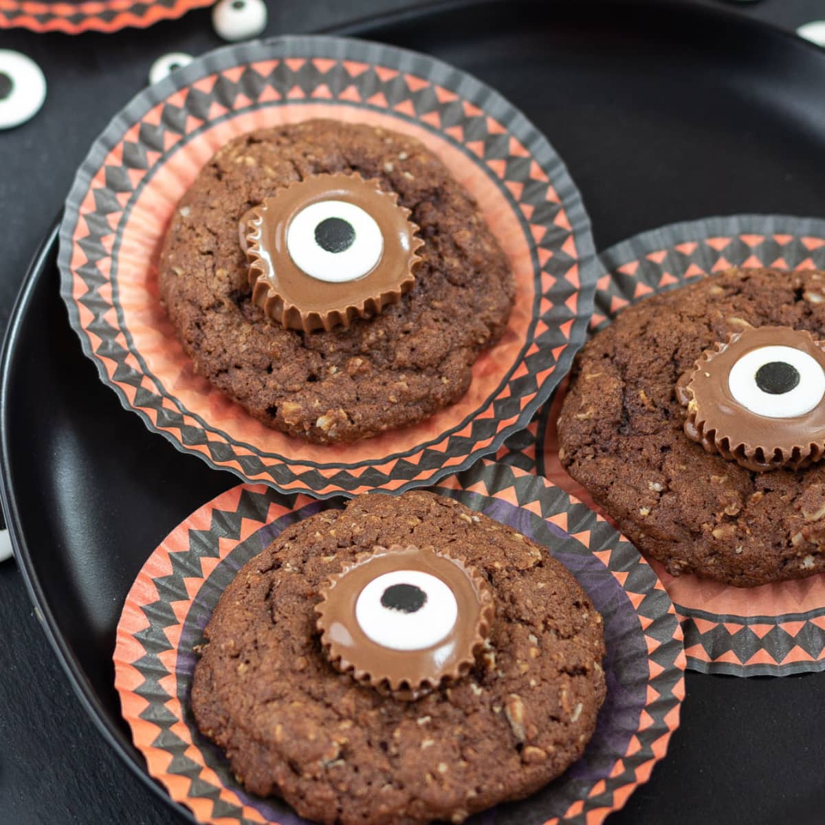 Round cupcake papers with chocolate cookies decorated with candy eyes