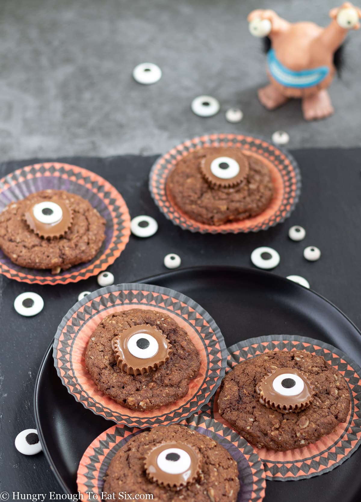 Chocolate cookies with candy eyes in the centers and scattered around
