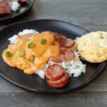 Cheese-topped sausage and rice on a plate.