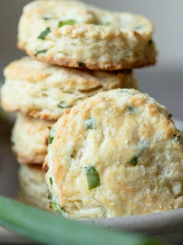 Biscuits with green onions stacked in a dish.