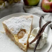 Slice of apple pie on plate with whipped cream.