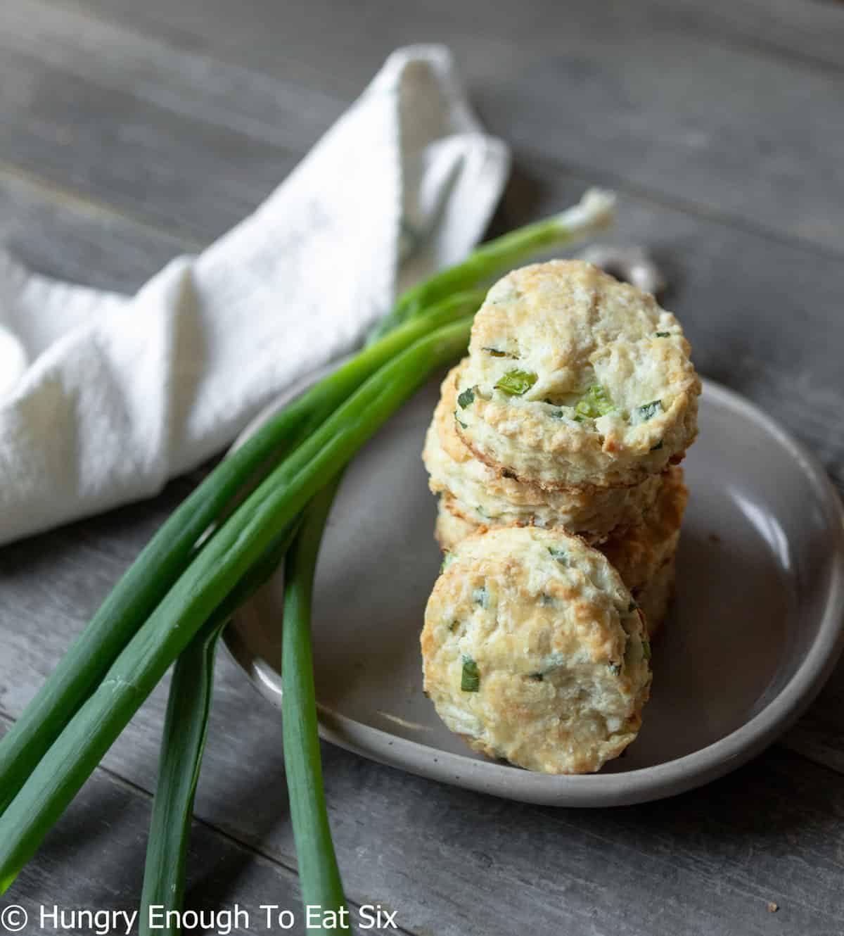 Baked round biscuits next to bunch of green onions.