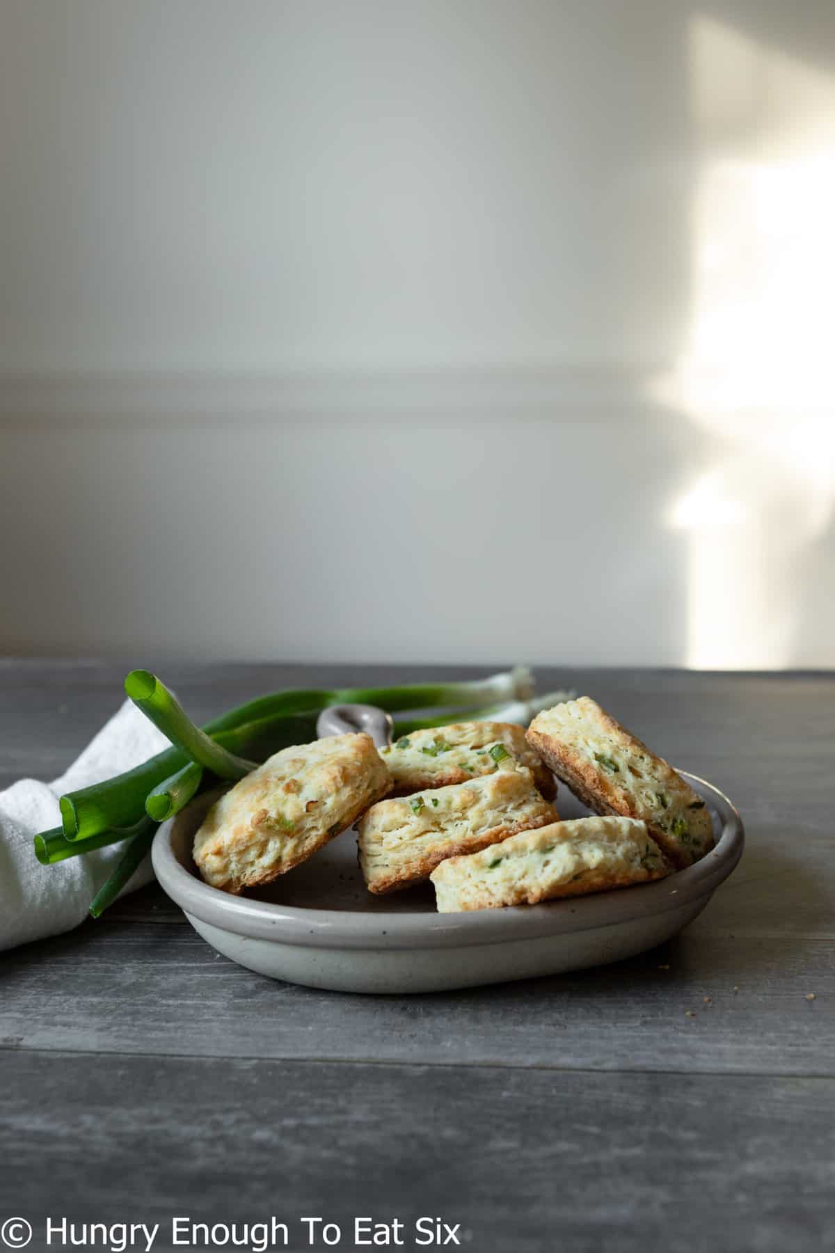 Gray plate with baked biscuits and fresh scallions.