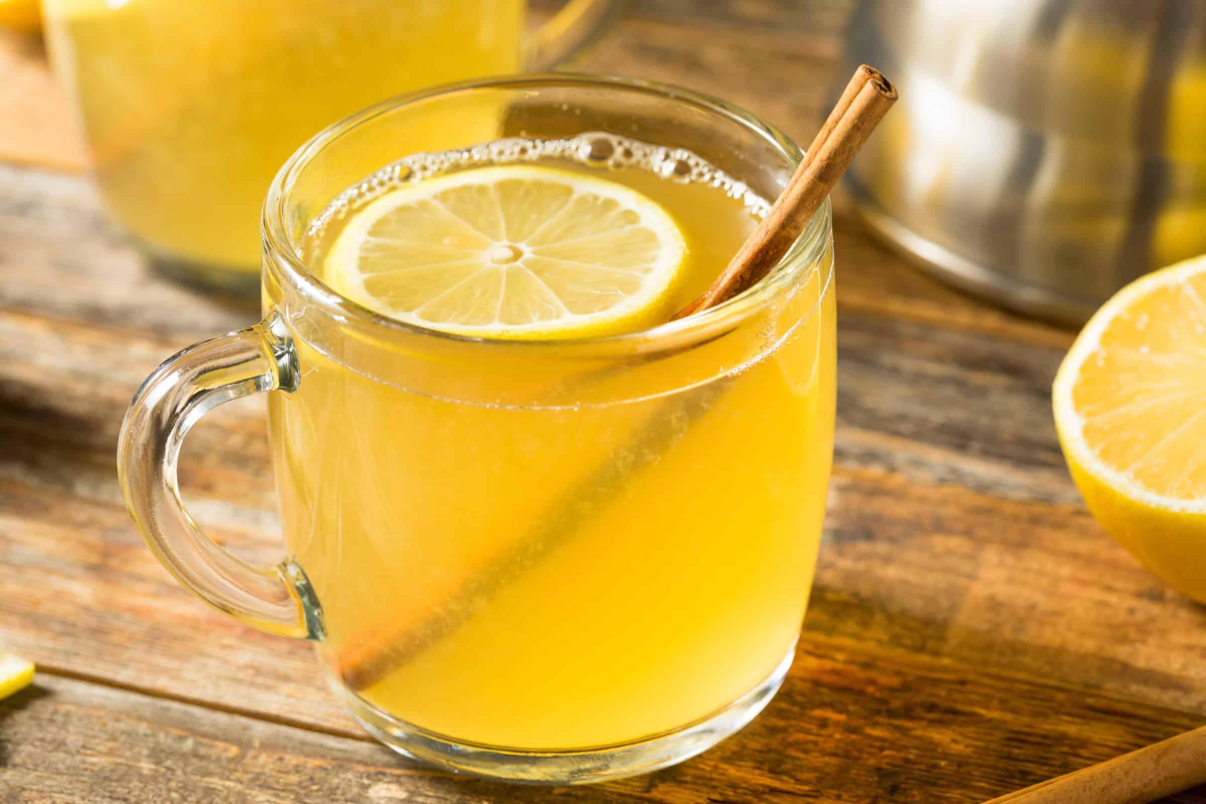 Glass with a hot toddy cocktail, lemon slice, and cinnamon stick.