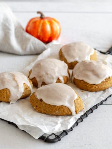 Frosted pumpkin flavored cookies on small cooling rack.