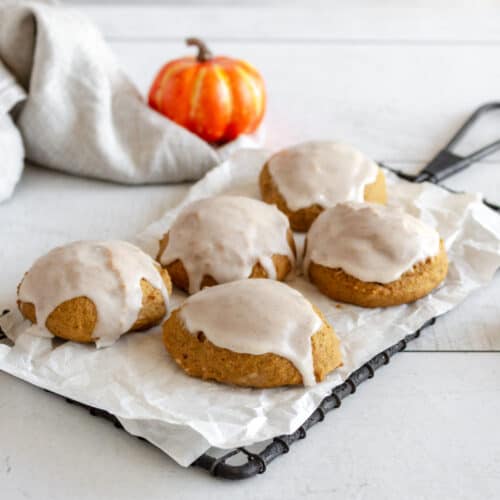 Frosted pumpkin flavored cookies on small cooling rack.