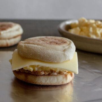 Assembled English muffin breakfast sandwich with cheese and sausage.
