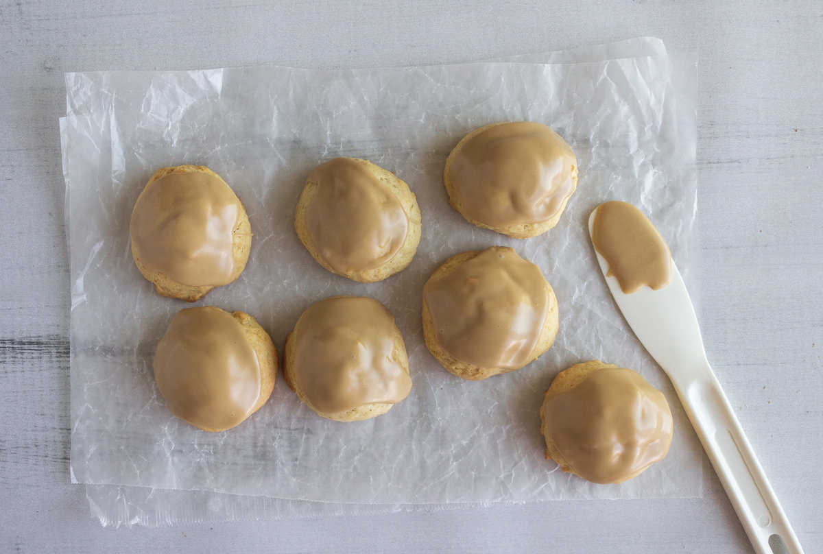Baked cookies with iced tops and a white spatula with icing.