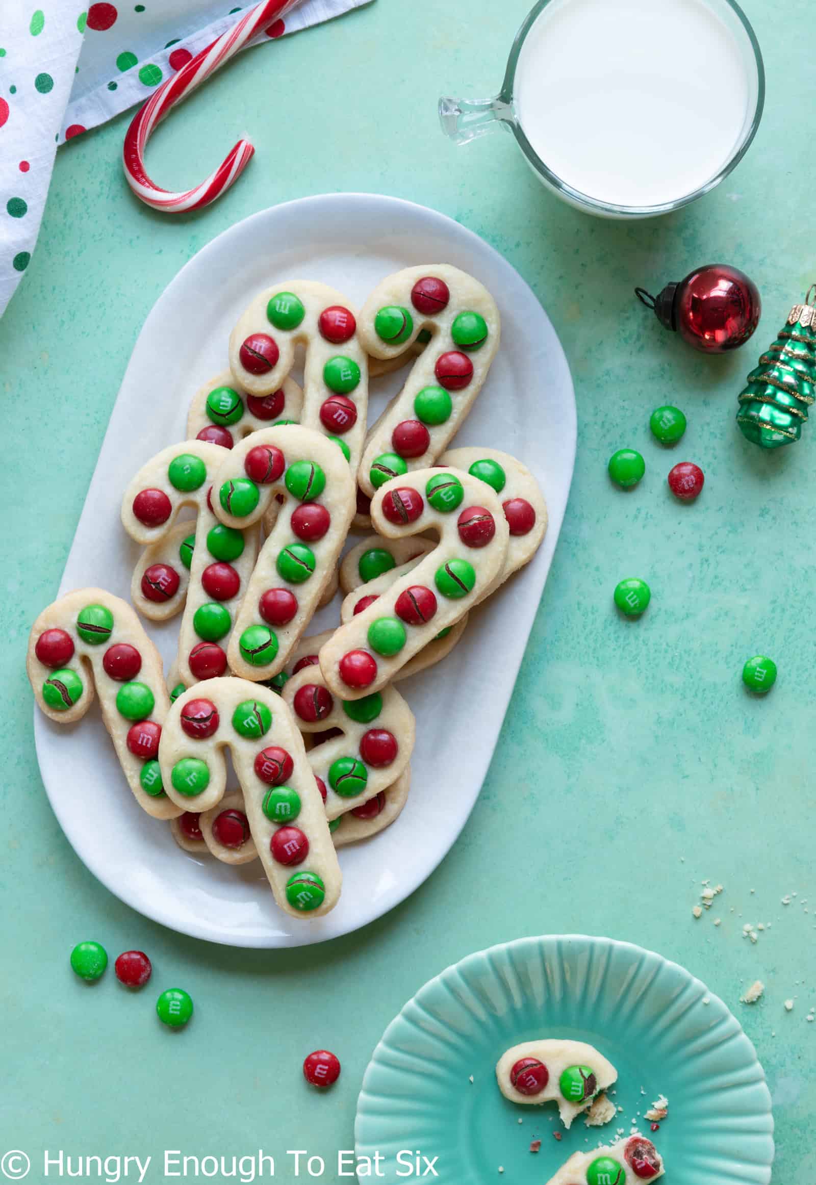 White plate with baked candy cane cookies decorated with red and green candies. 