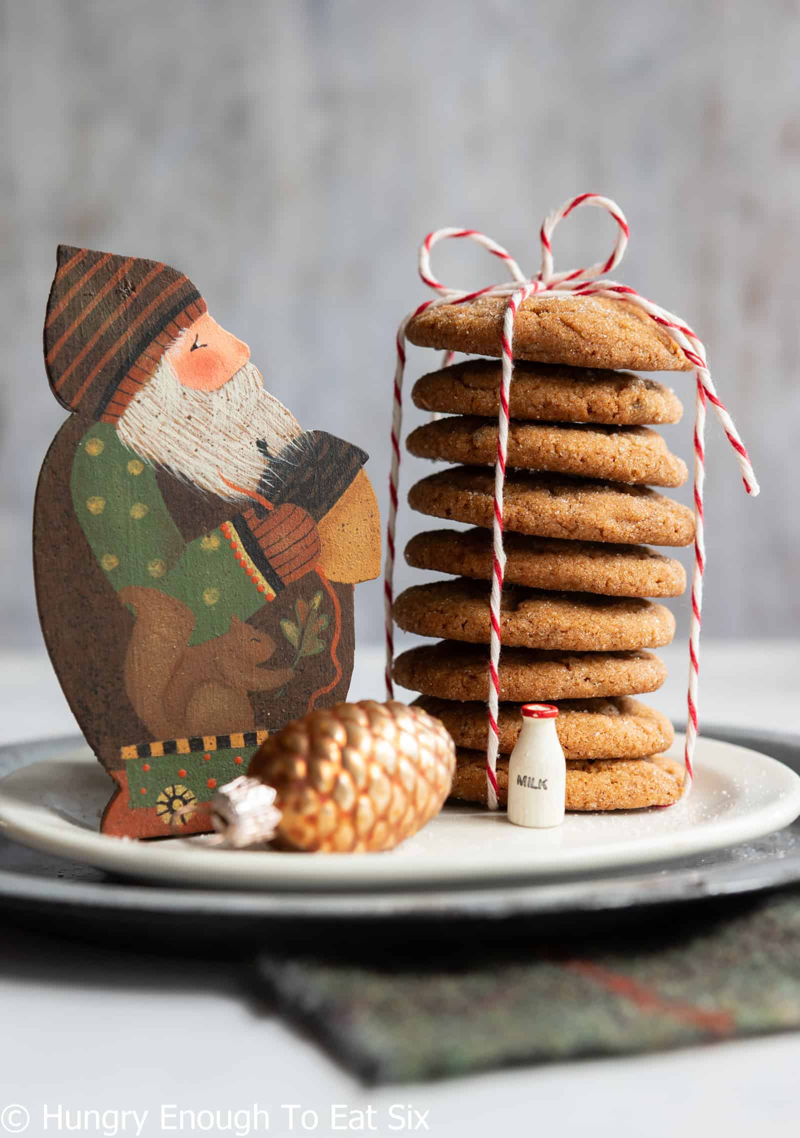 Stack of ginger cookies tied with string next to a painted woodland Santa Claus.