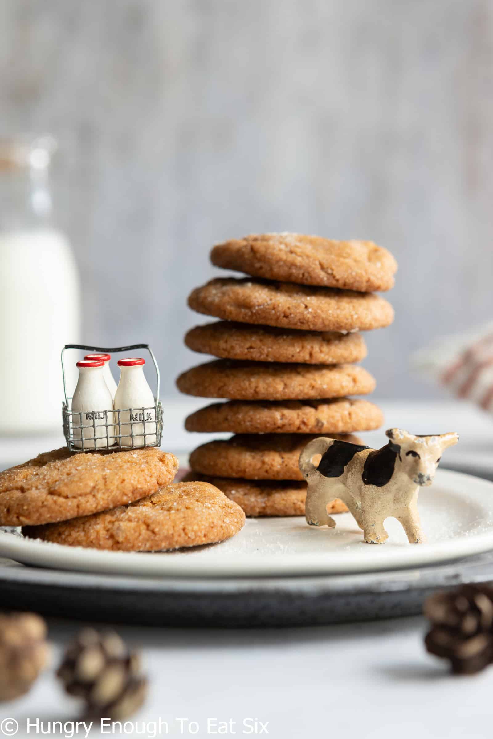 Ginger cookies stack on a plate with a tiny toy cow.