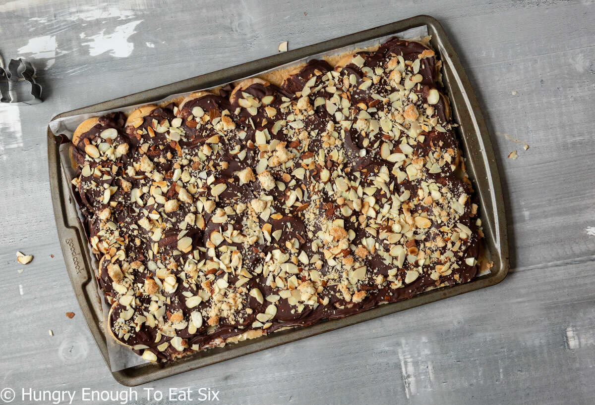 Baking sheet with nut topped chocolate candy.