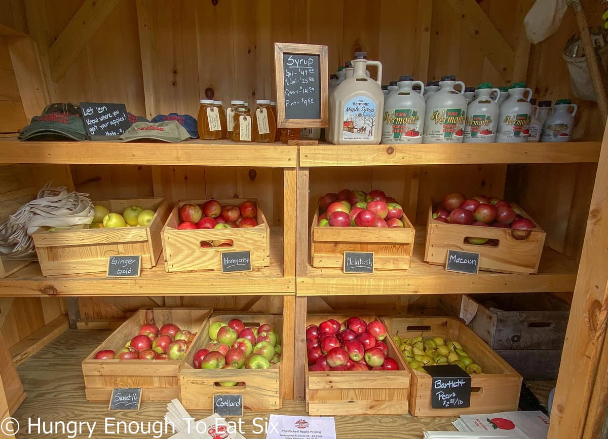 Syrup and boxes of apples inside wood shed.