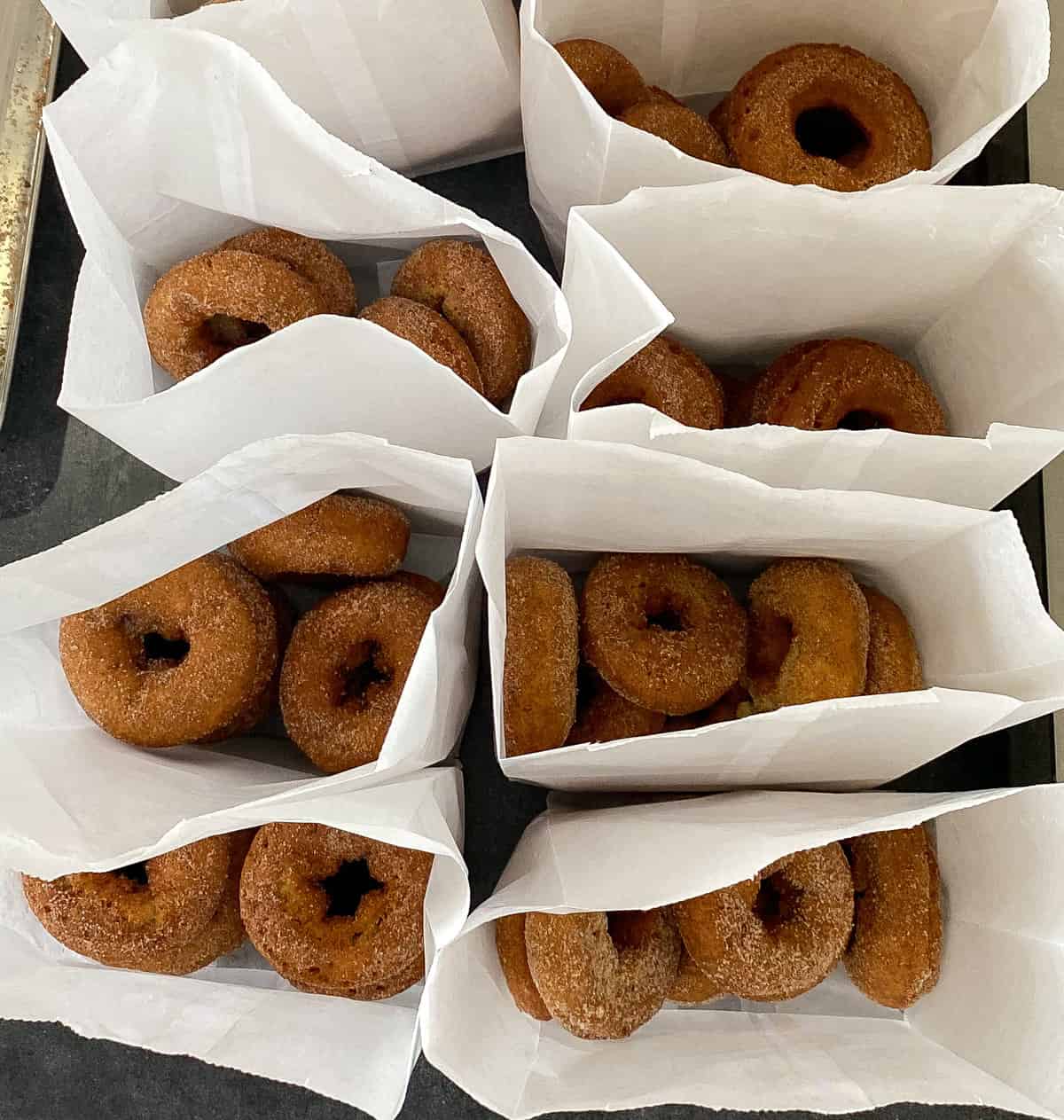 White paper bags filled with apple cider donuts.