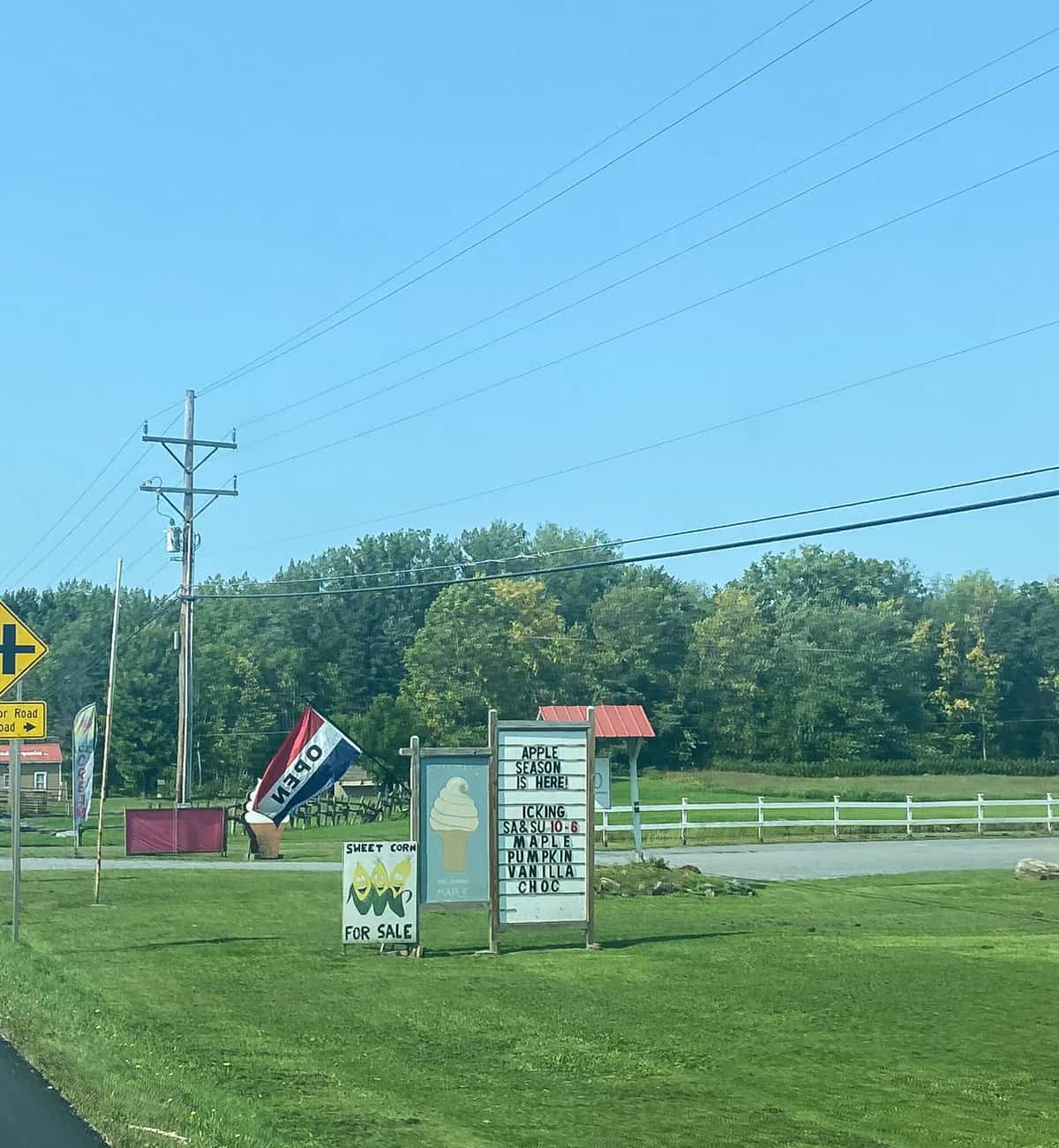 Roadside sign for apple picking and ice cream with "open" flag.