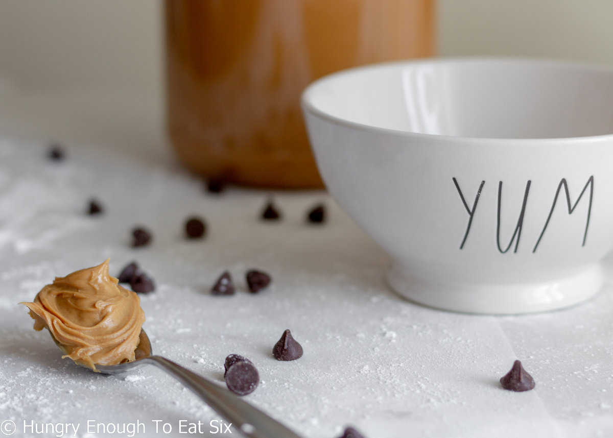 White bowl that says Yum and a spoonful of peanut butter.