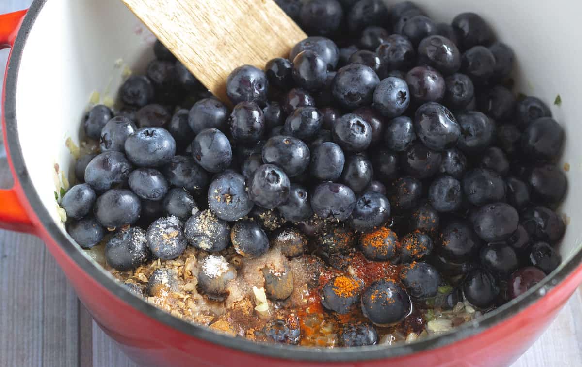 Pot with blueberries, spices, and diced aromatics.