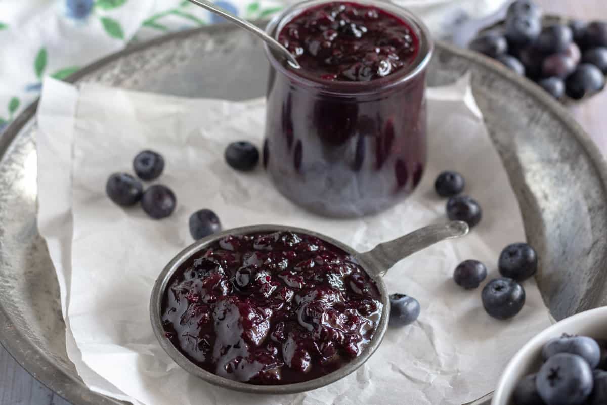 Jar and measuring spoon of blueberry ketchup.