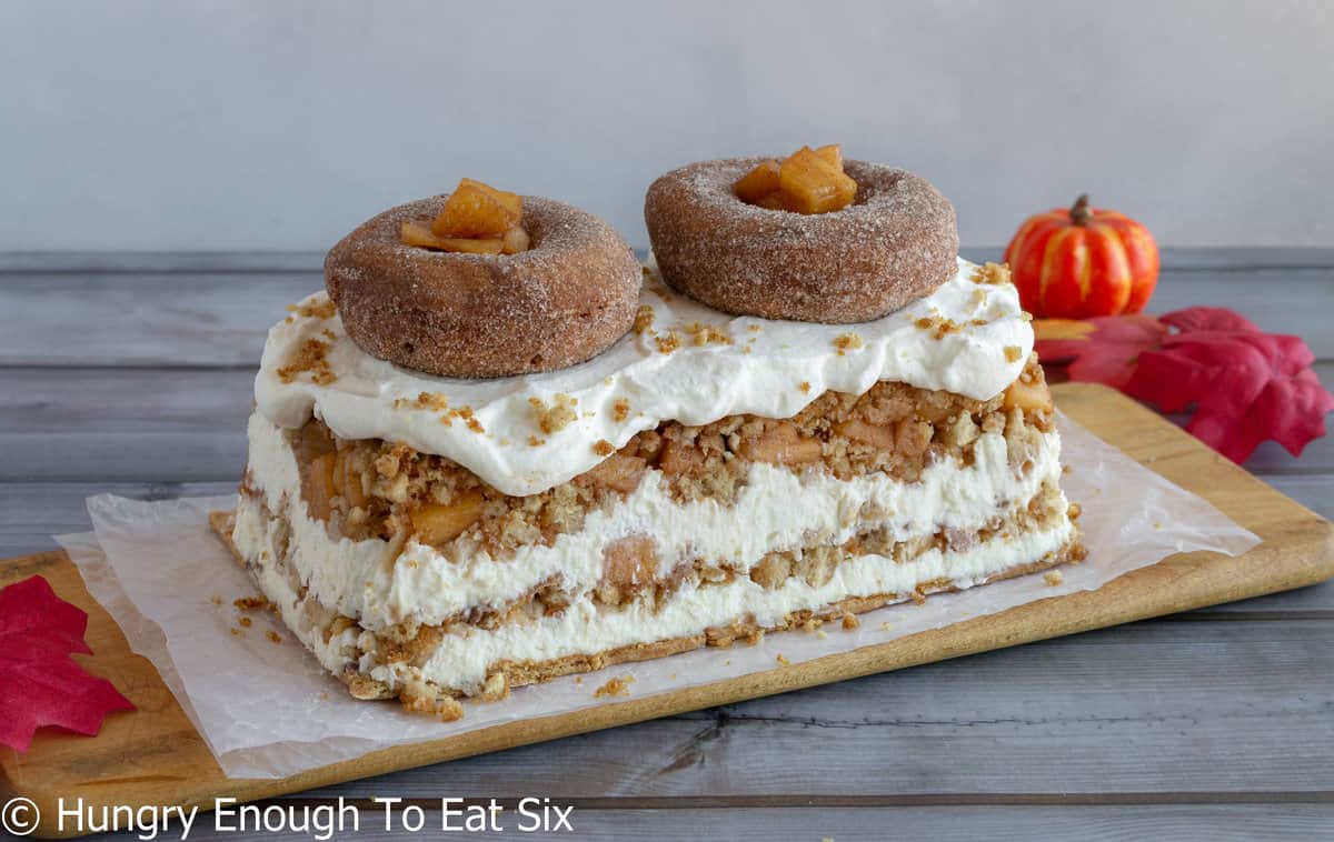 Layered icebox cake with whole donuts and diced apples on top.