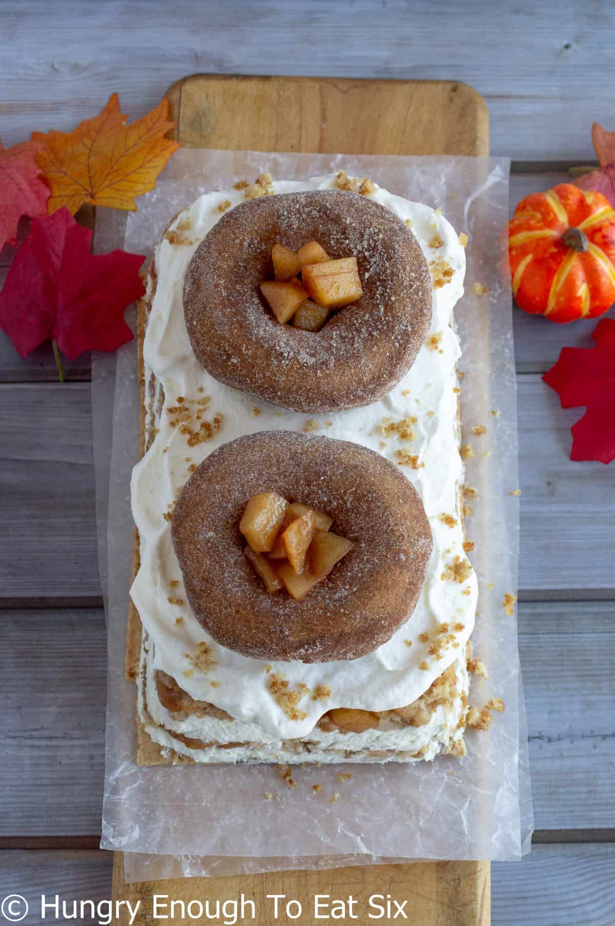 Donuts on top of an icebox cake with cream and apples.