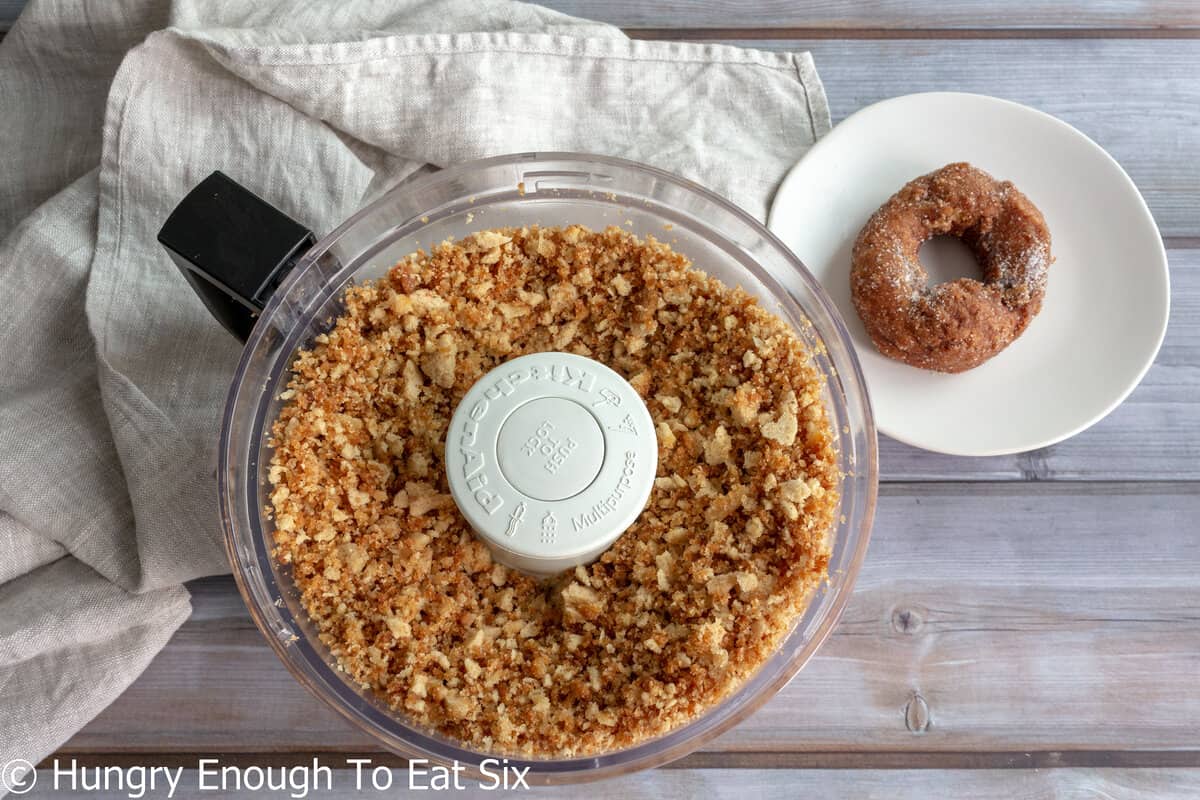 Donuts processed to crumbs inside a food processor bowl.