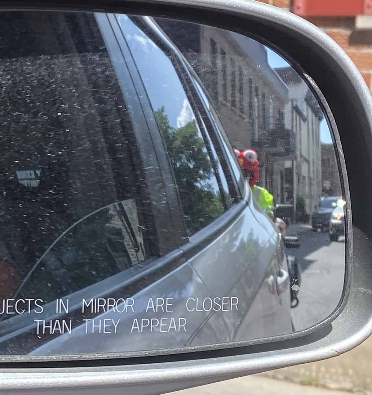 Image of Elmo face in a car side view window.