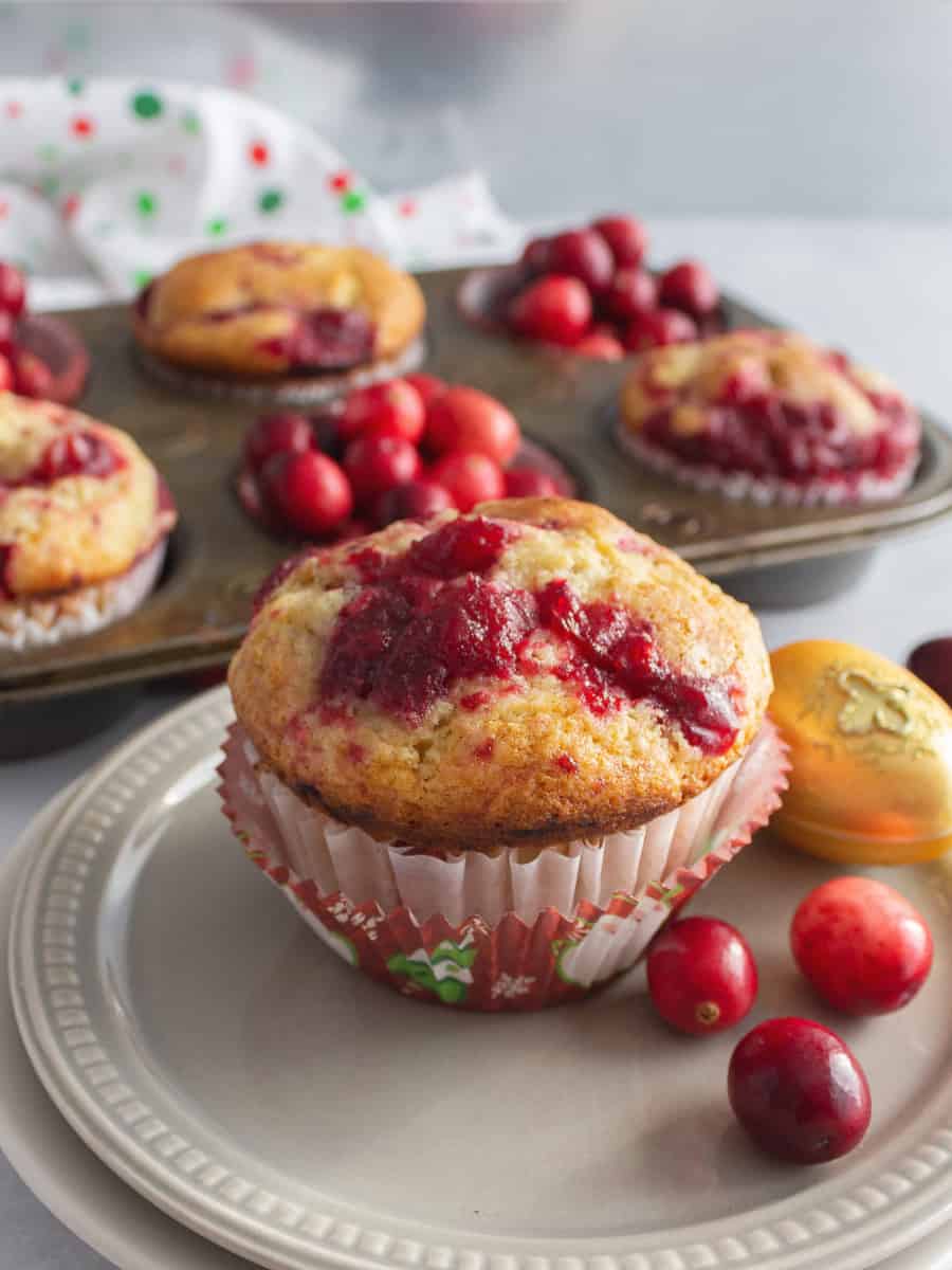 Muffin with cranberries with muffins and whole berries in background.