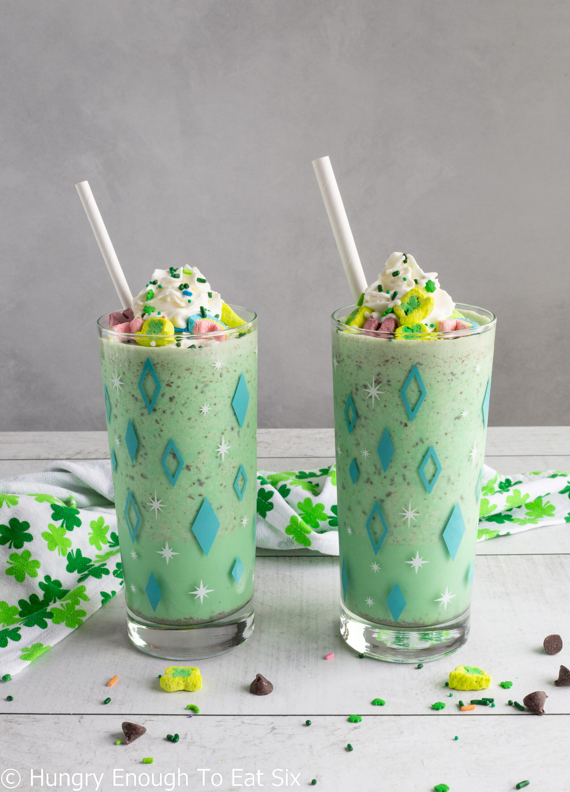 Milkshakes in tall glasses with whipped cream and straws.