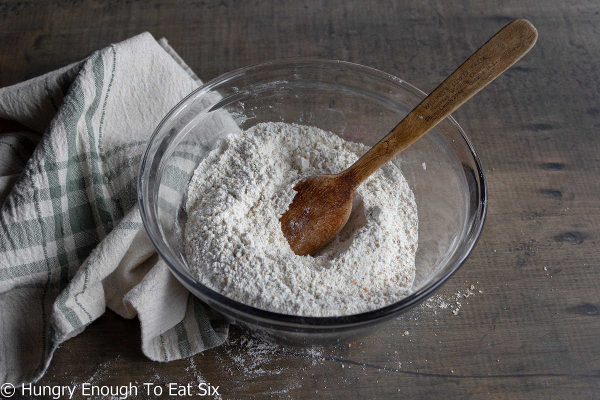 Flours mixed in a glass bowl with a wooden spoon.