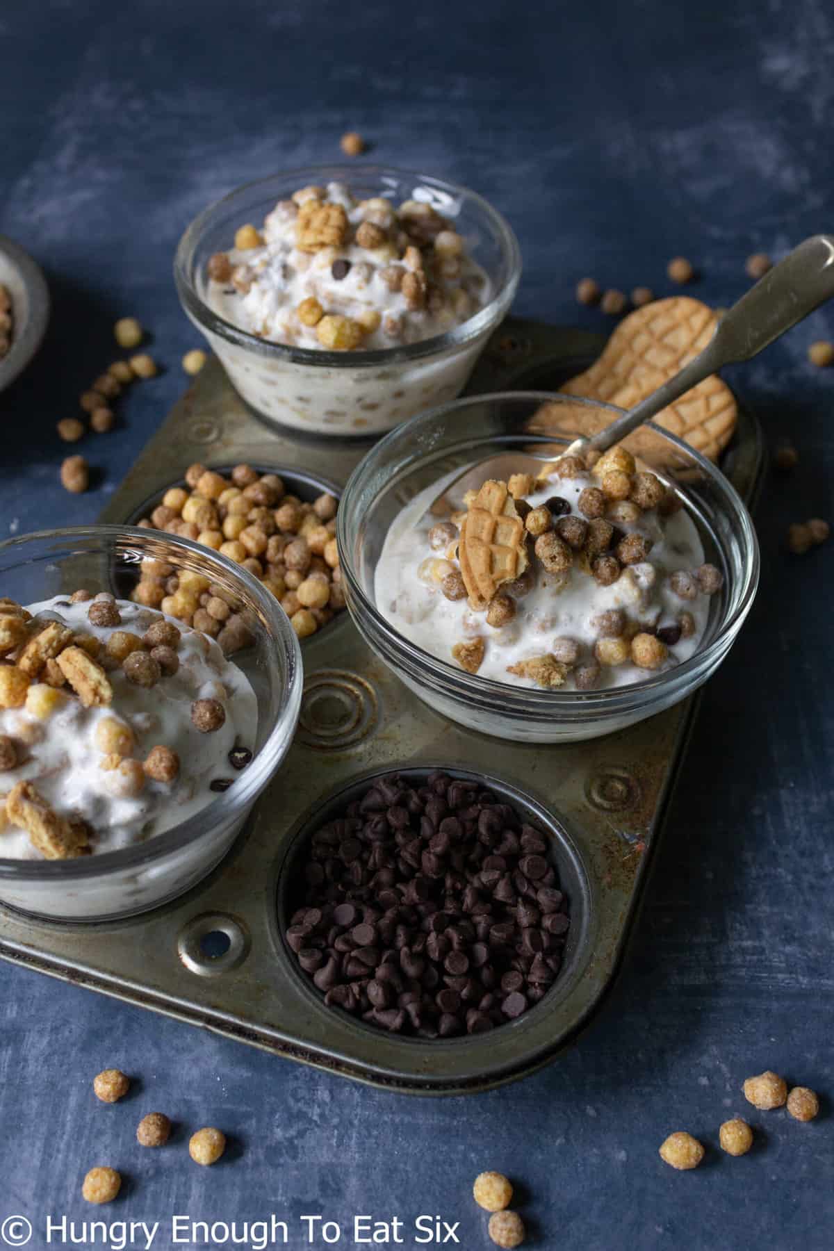 Pan holding chocolate chips, cereal, and dishes of ice cream.