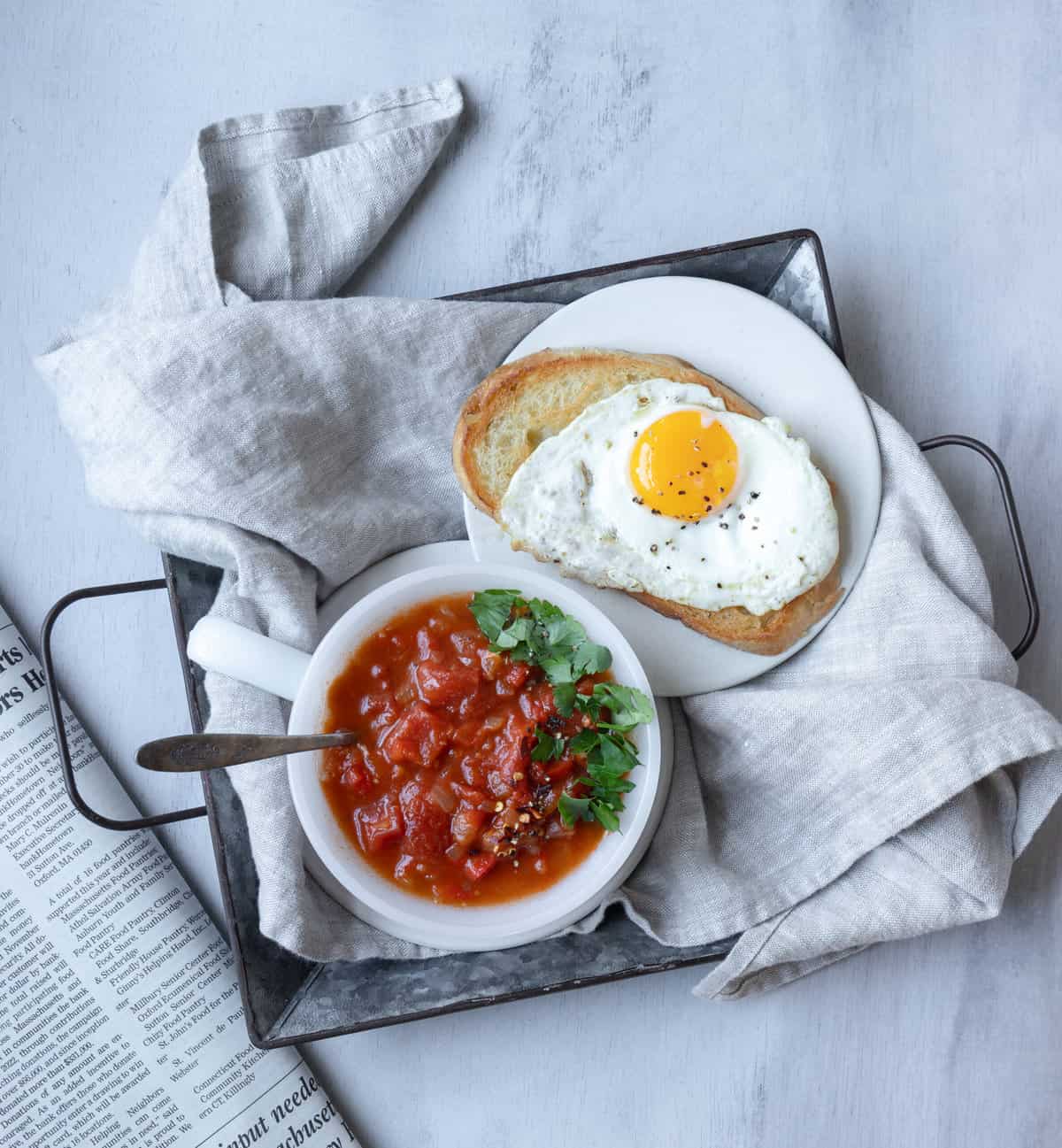 Bowl of tomato soup with fried egg on toast.