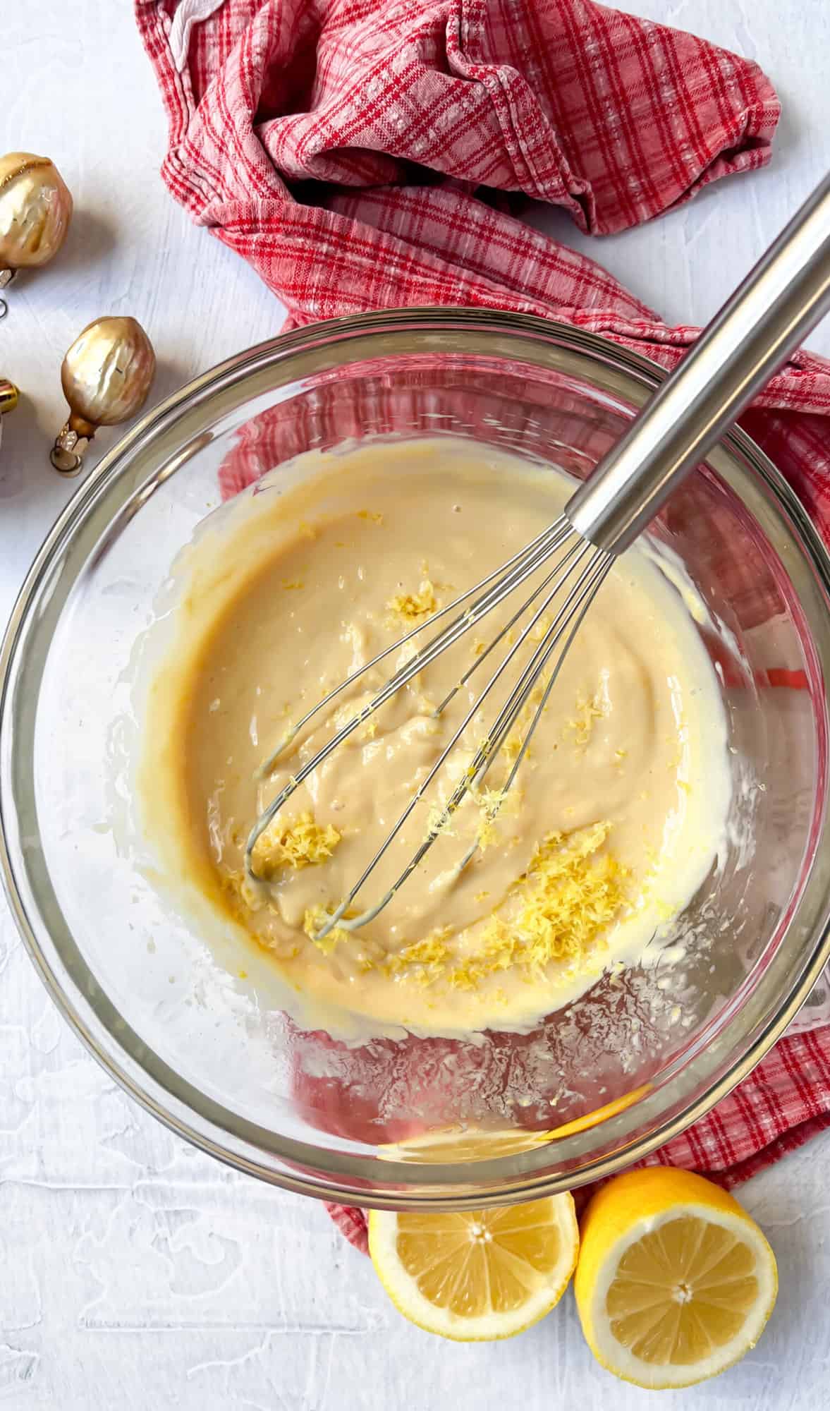 Creamy mixture in mixing bowl with whisk and lemon zest.