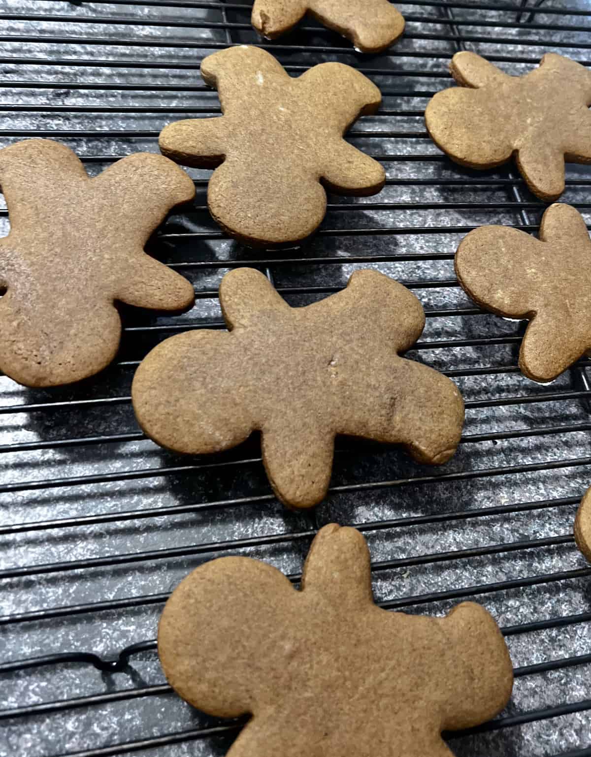 Baked gingerbread boy cookies on a rack.