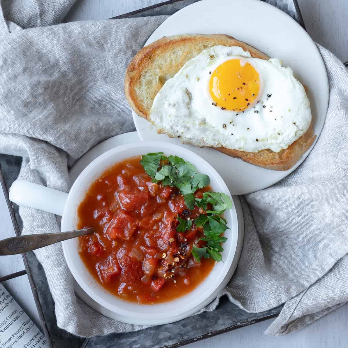 Bowl of thick tomato soup with fried egg on bread.