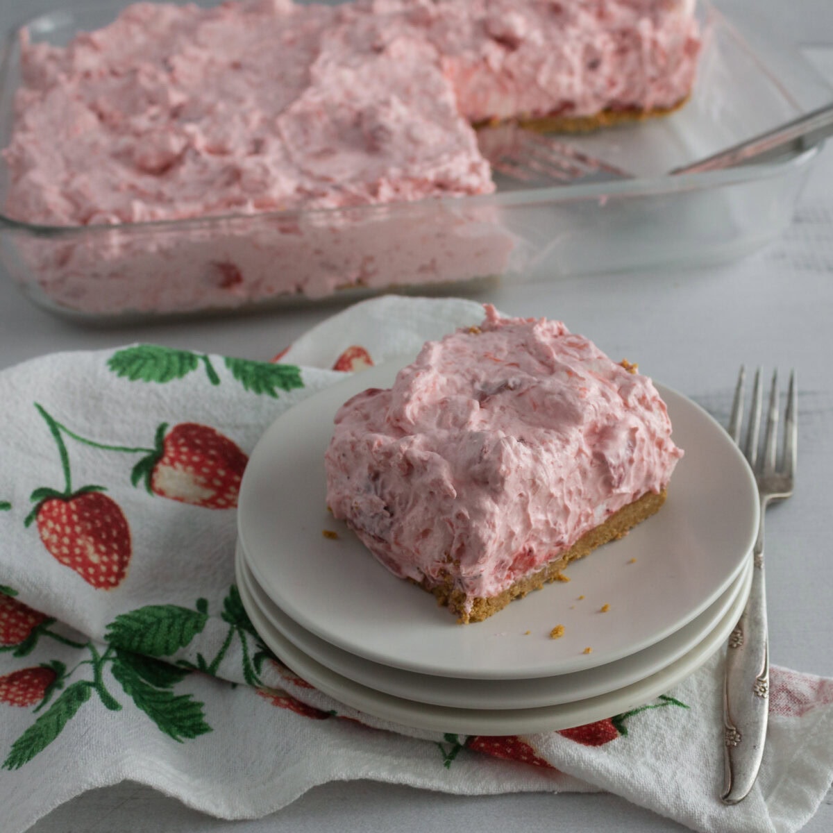 Slice of pink whipped cream dessert on plate.
