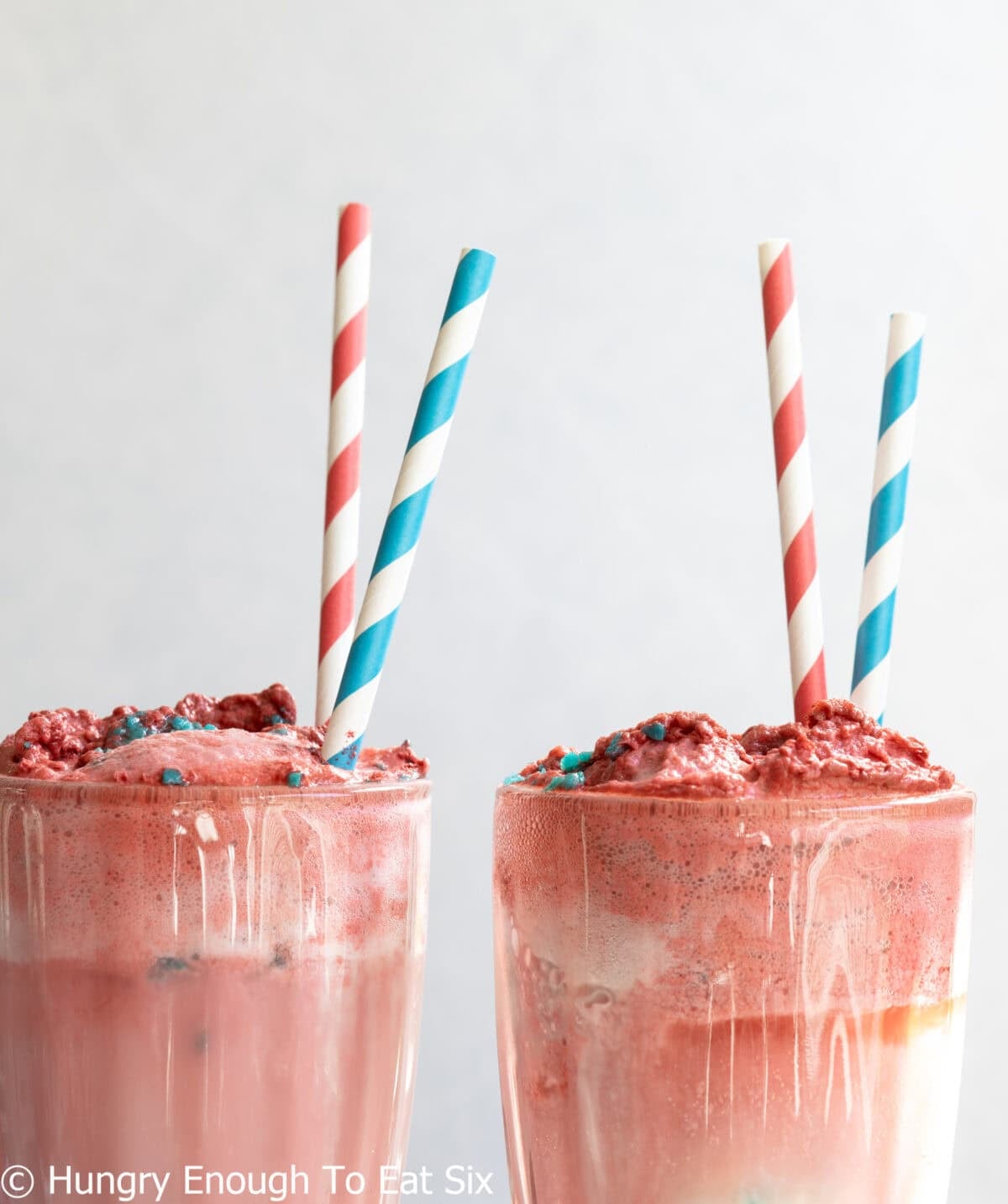 Red and white and blue striped straws in red ice cream floats.