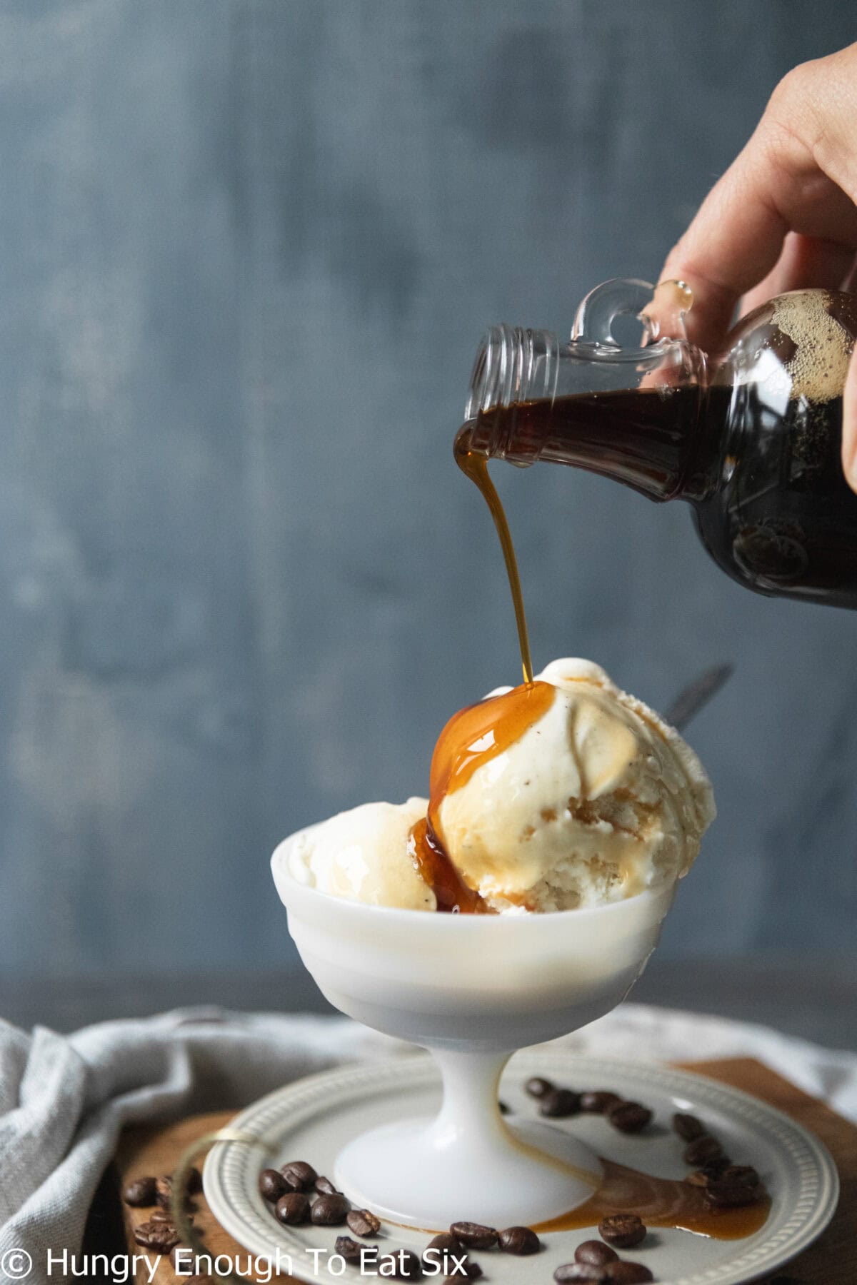 Bowl of ice cream with syrup pouring over top.