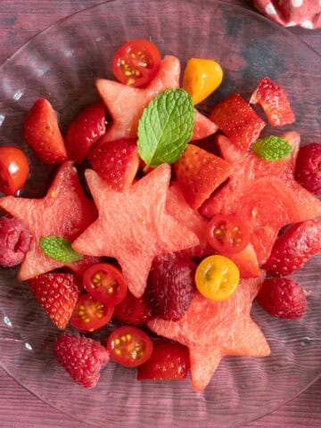 Fruit salad on a plate with tomatoes and watermelon stars.