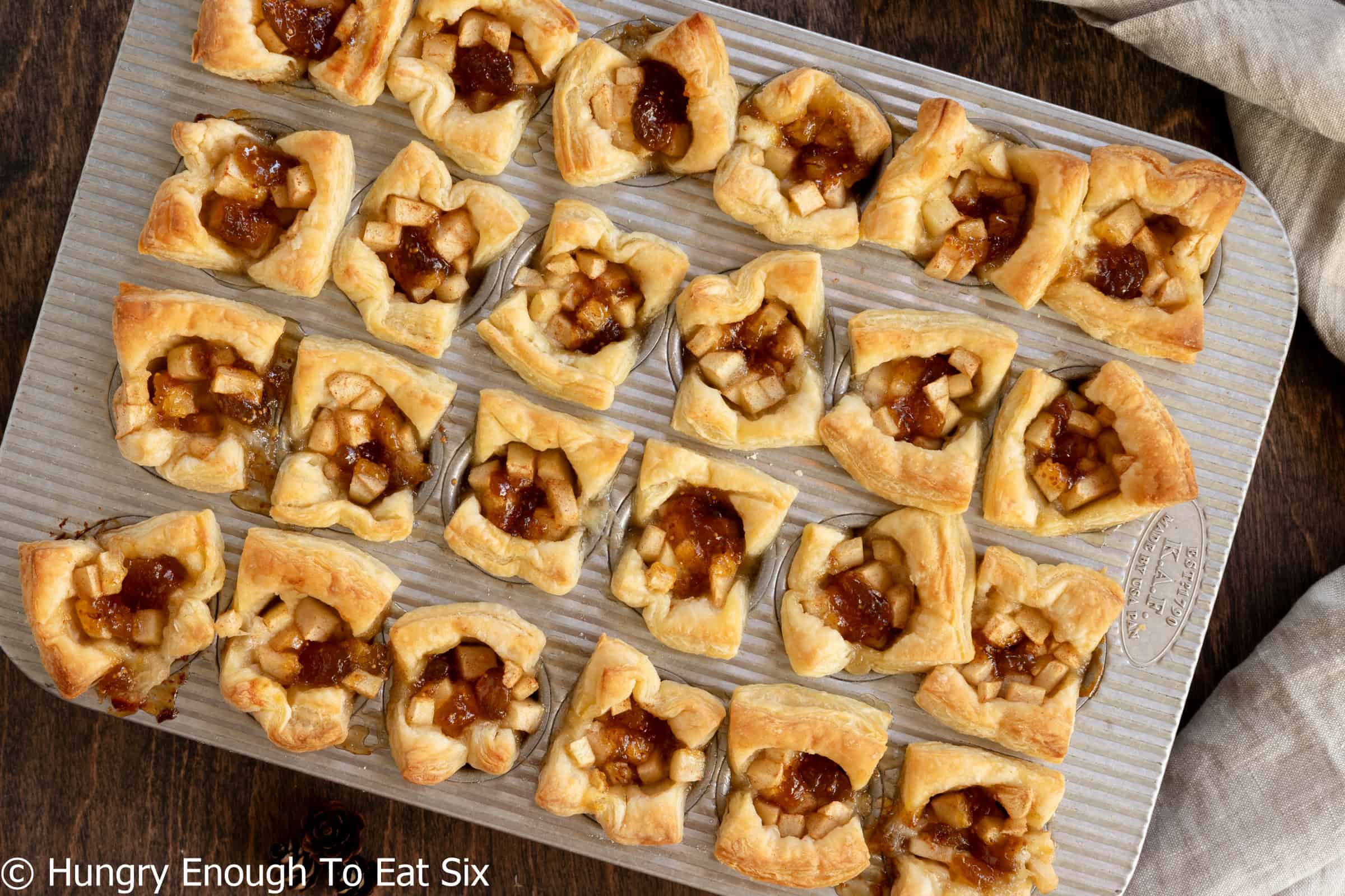 Muffin pan full of baked apple and fig brie bites in pastry.