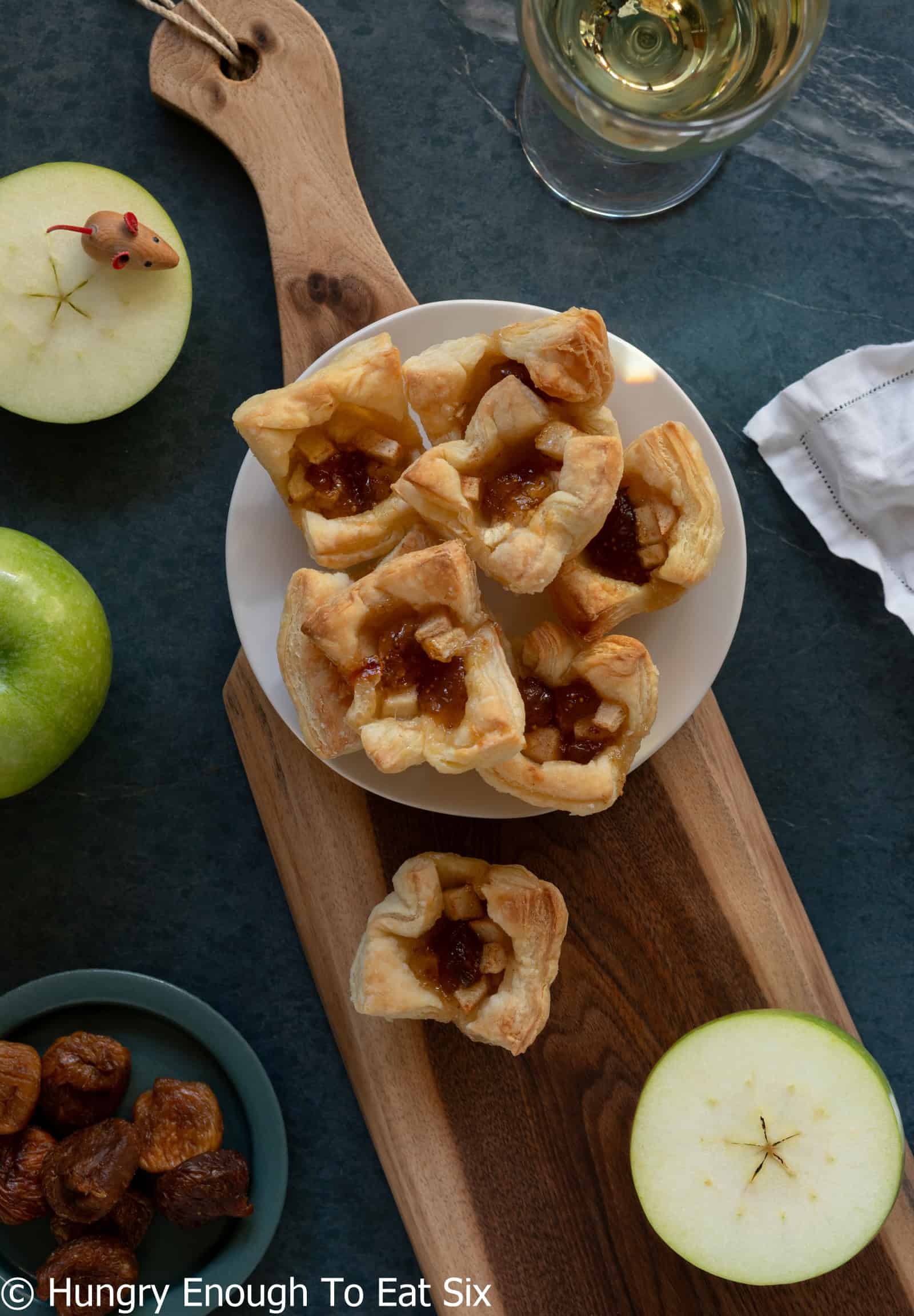 Baked puff pastry fig and apple bites on a charcuterie board with apples.