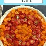 Round baked tart with dozens of slices of cherry tomatoes.