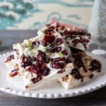 White plate with white chocolate bark with cranberries and nuts.