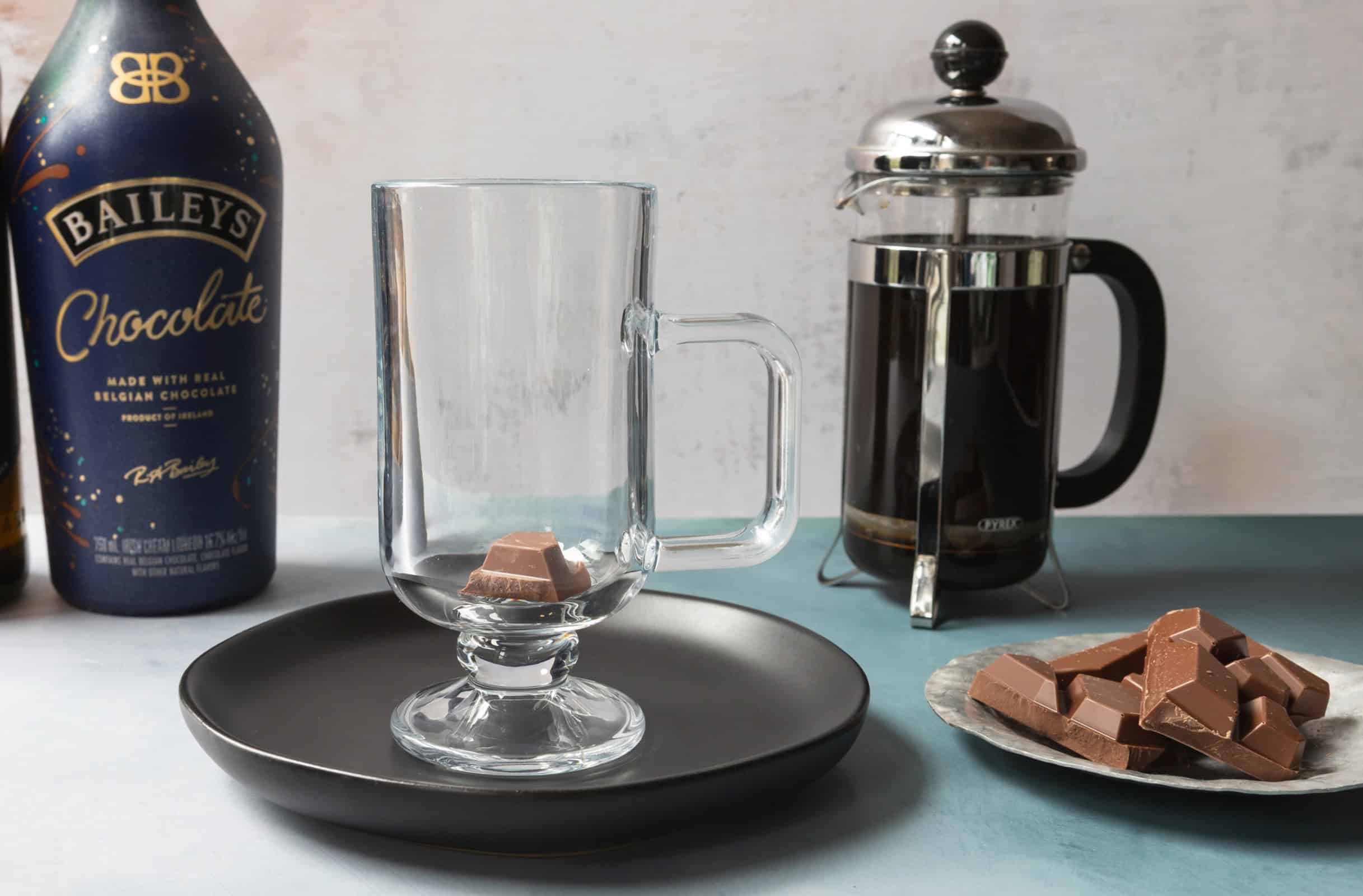 Irish coffee glass with cocoa powder, whiskey, and chocolate Baileys.