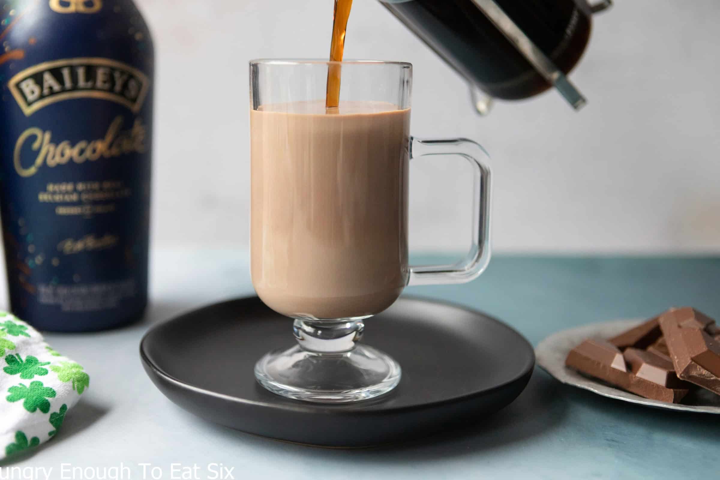 Pouring coffee into a glass mug with whiskey and chocolate liqueur, for a chocolate Irish coffee.